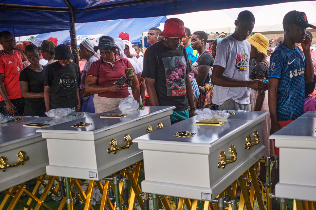 Family members walk past caskets carrying their loved ones during a memorial service for the victims of a ferry that capsized on Lake Kariba in Kariba, Zimbabwe, Thursday, Aug. 13, 2026. (AP Photo/Mkhululi Thobela)