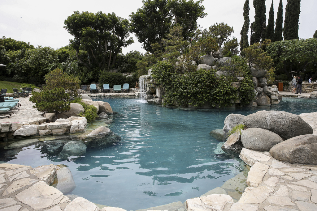FILE - A waterfall flows into a pool on the grounds at the Playboy Mansion in Los Angeles, May 11, 2016. (Photo by John Salangsang/Invision/AP, File)