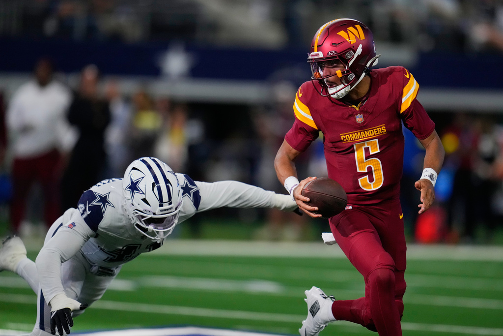 Washington Commanders quarterback Jayden Daniels (5) avoids a tackle by Dallas Cowboys defensive end Donovan Ezeiruaku during the first half of an NFL football game Sunday, Oct. 19, 2025, in Arlington, Texas. (AP Photo/Jeffrey McWhorter)
