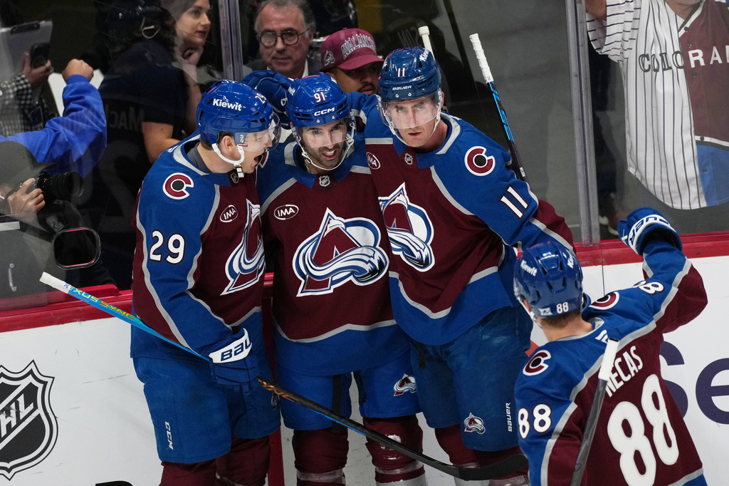 Colorado Avalanche center Nazem Kadri, center, is congratulated after scoirng a power play goal by center Nathan MacKinnon, left, and center Brock Nelson, right, as Colorado Avalanche center Martin Necas, front, joins in in the first period of an NHL hockey game against the Calgary Flames, Monday, March 30, 2026, in Denver. (AP Photo/David Zalubowski)