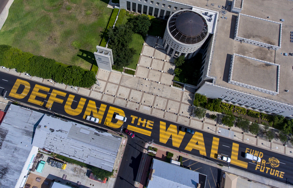Cars drive over giant, yellow letters painted on Victoria Street in front of the federal courthouse in Laredo, Texas, Aug. 18, 2020. (William Luther/The San Antonio Express-News via AP)