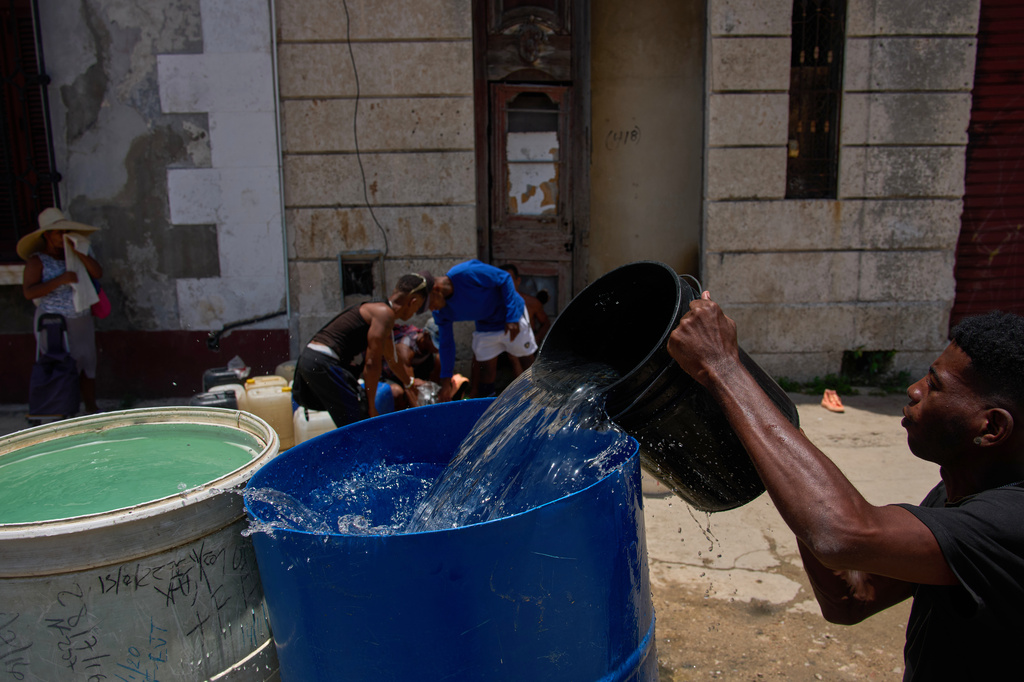 People collect water from a street tap during a blackout in Havana, Cuba, Tuesday, July 14, 2026. (AP Photo/Ramon Espinosa)
