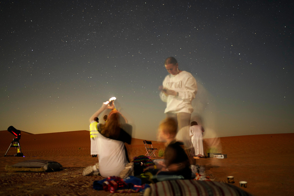 This long-exposure photograph shows a family taking mobile phone pictures in the Al Quaa Desert outside of Abu Dhabi, United Arab Emirates, Saturday, May 23, 2026. (AP Photo/Jon Gambrell)