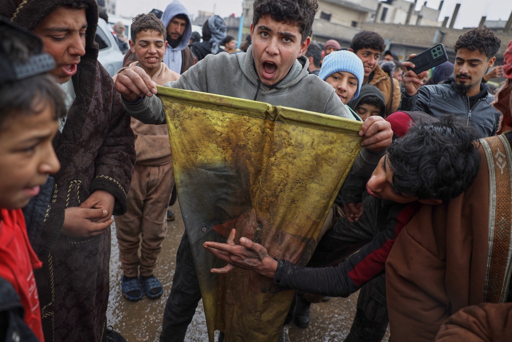 Local youth tear up an SDF flag as they celebrate after Syrian government troops took control of the town from U.S.-backed Syrian Democratic Forces (SDF) during an ongoing push against Kurdish-led forces, in Tabqa, eastern Syria, Sunday, Jan. 18, 2026. (AP Photo/Omar Albam)