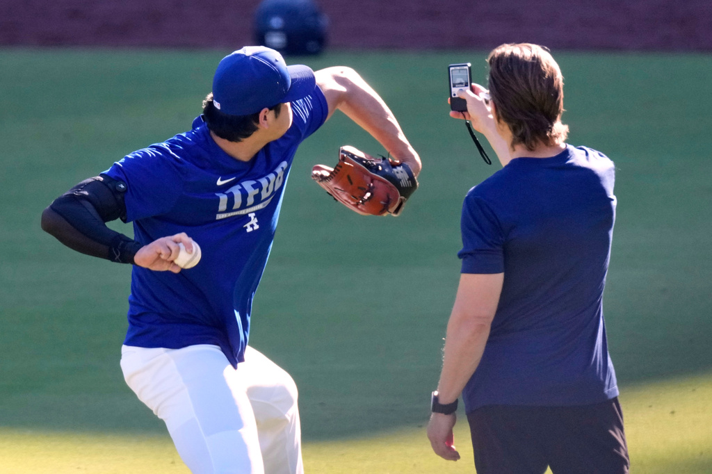 Los Angeles Dodgers' Shohei Ohtani warms up with a trainer prior to a baseball game against the Pittsburgh Pirates, Friday, Aug. 21, 2026, in Los Angeles. (AP Photo/Mark J. Terrill)