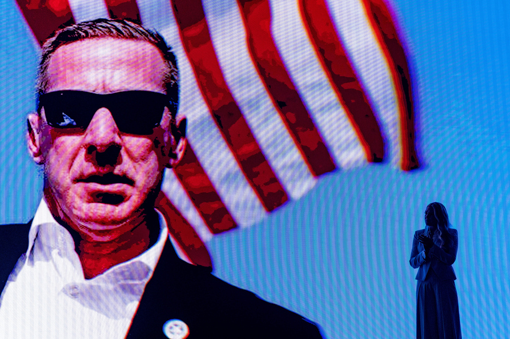 Erika Kirk stands as a video of the assassination attempt of President Donald Trump plays behind her at a Turning Point USA event at Dream City Church, Friday, April 17, 2026, in Phoenix. (AP Photo/Alex Brandon)