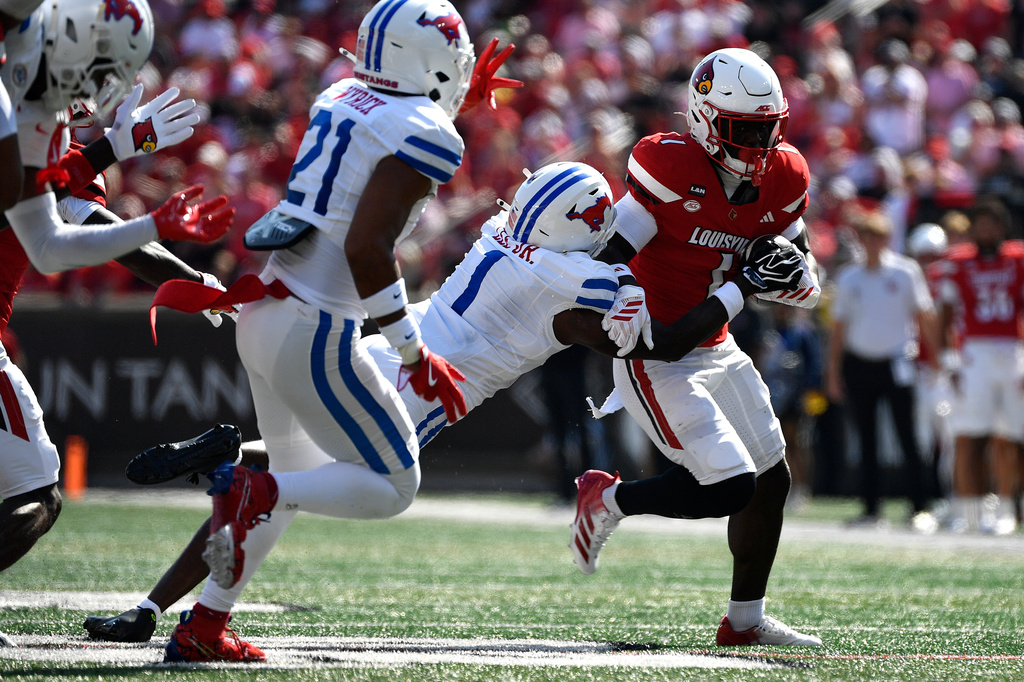 Louisville running back Isaac Brown, right, is grabbed by SMU safety Jarvis Lee, second from right, during the first half of an NCAA college football game in Louisville, Ky., Saturday, Sept. 19, 2026. (AP Photo/Timothy D. Easley)