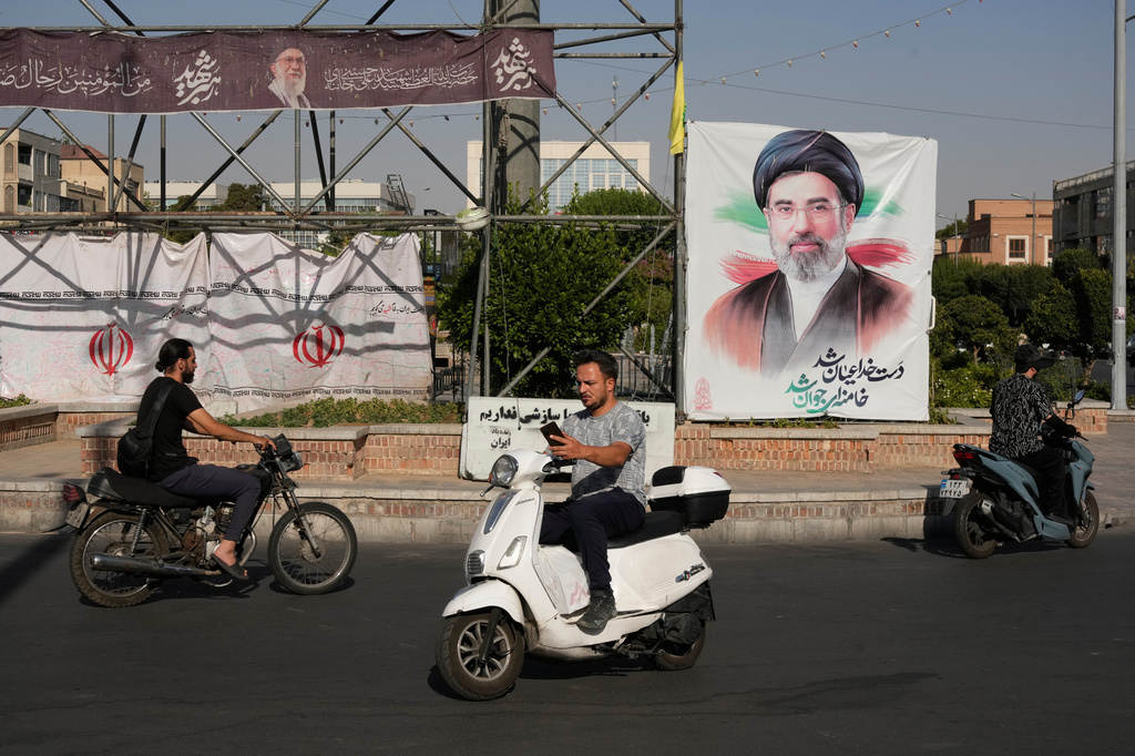 Motorbikes drive past a banner showing a portrait of the Iranian Supreme Leader Ayatollah Mojtaba Khamenei in downtown Tehran, Iran, Monday, June 29, 2026. (AP Photo/Vahid Salemi)