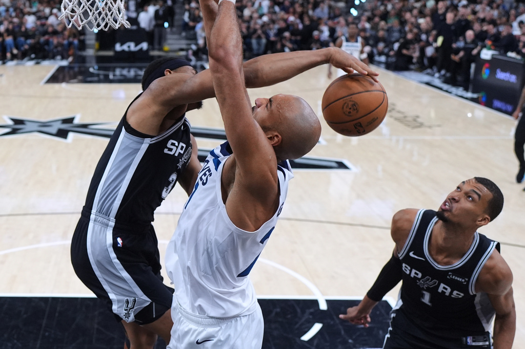 Minnesota Timberwolves center Rudy Gobert, center, is blocked by San Antonio Spurs forward Keldon Johnson (3) as forward Victor Wembanyama (1) looks on during the second half of Game 5 of an NBA basketball second-round playoffs series in Minneapolis, Tuesday, May 12, 2026. (AP Photo/Eric Gay)