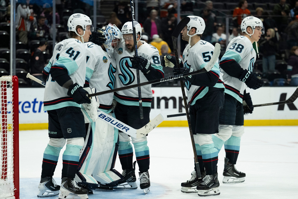Seattle Kraken players celebrate the team's win over the Anaheim Ducks in an NHL hockey game, Monday, Dec. 22, 2025, in Anaheim, Calif. (AP Photo/Kyusung Gong)