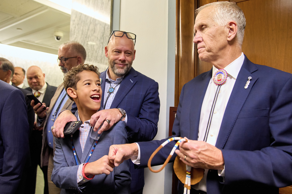 Austin Curt Thomas, 11, gets a celebratory fist bump from Sen. Thom Tillis, R-N.C., as he and his father Aaron Thomas, of Pembroke, N.C., join fellow members of the Lumbee Tribe of North Carolina, to celebrate after the passage of a bill granting their people federal recognition, on Capitol Hill, in Washington, Wednesday, Dec. 17, 2025. (AP Photo/Jacquelyn Martin)