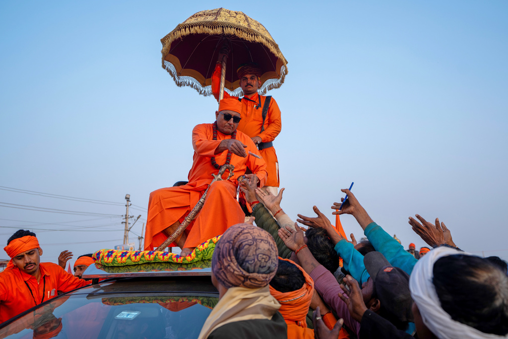A Hindu holy man distributes food while sitting on the top of his vehicle on the eve of Mauni Amavasya, a divine occasion in Hindu religious practice followed for honoring ancestors or forefathers, at the Sangam, the confluence of the Ganges, the Yamuna and the mythical Saraswati rivers, during the annual month long Hindu religious fair "Magh Mela" in Prayagraj, India, Saturday, Jan.17, 2026. (AP Photo/Rajesh Kumar Singh)
