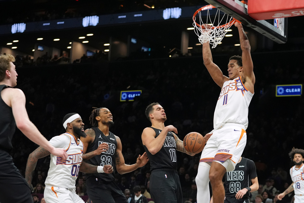 Phoenix Suns' Oso Ighodaro (11) dunks the ball in front of Brooklyn Nets' Michael Porter Jr. (17) during the first half of an NBA basketball game Monday, Jan. 19, 2026, in New York. (AP Photo/Frank Franklin II)