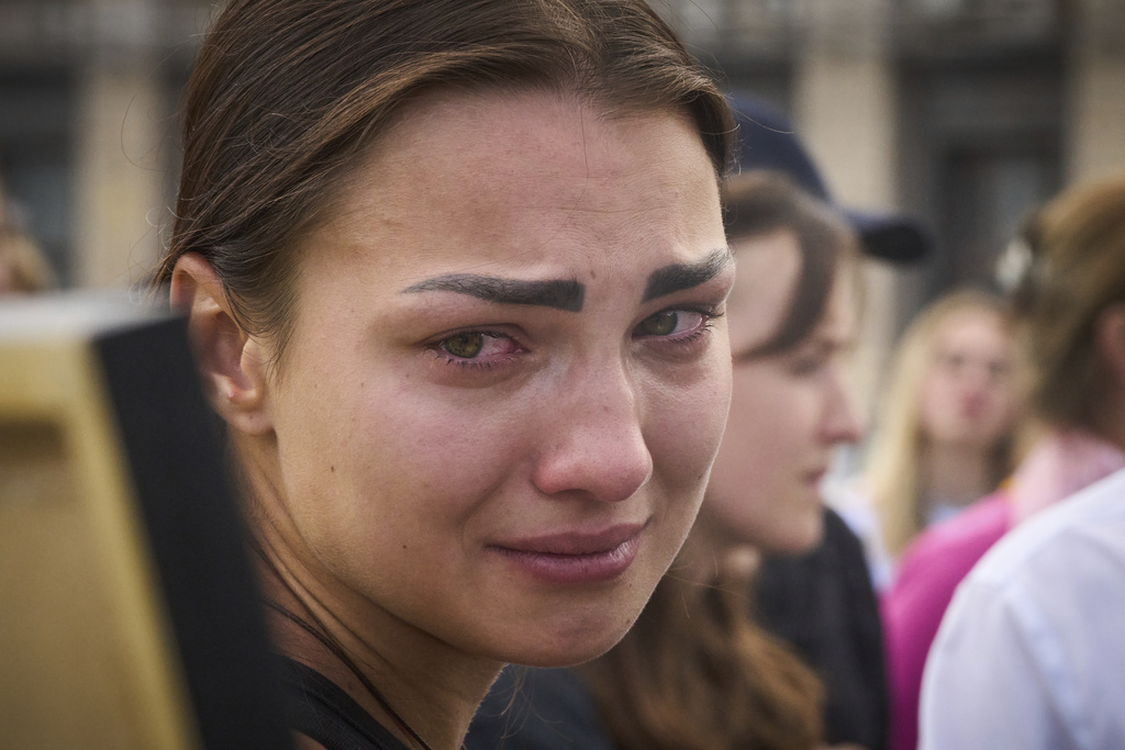 A colleague cries as she looks at a portrait of Victoria Roshchyna, 27, a Ukrainian journalist who reported on the Russian invasion of Ukraine and died in Russian captivity, during the funeral ceremony in the Independence square in central Kyiv, Ukraine, Friday, Aug. 8, 2025. (AP Photo/Efrem Lukatsky)