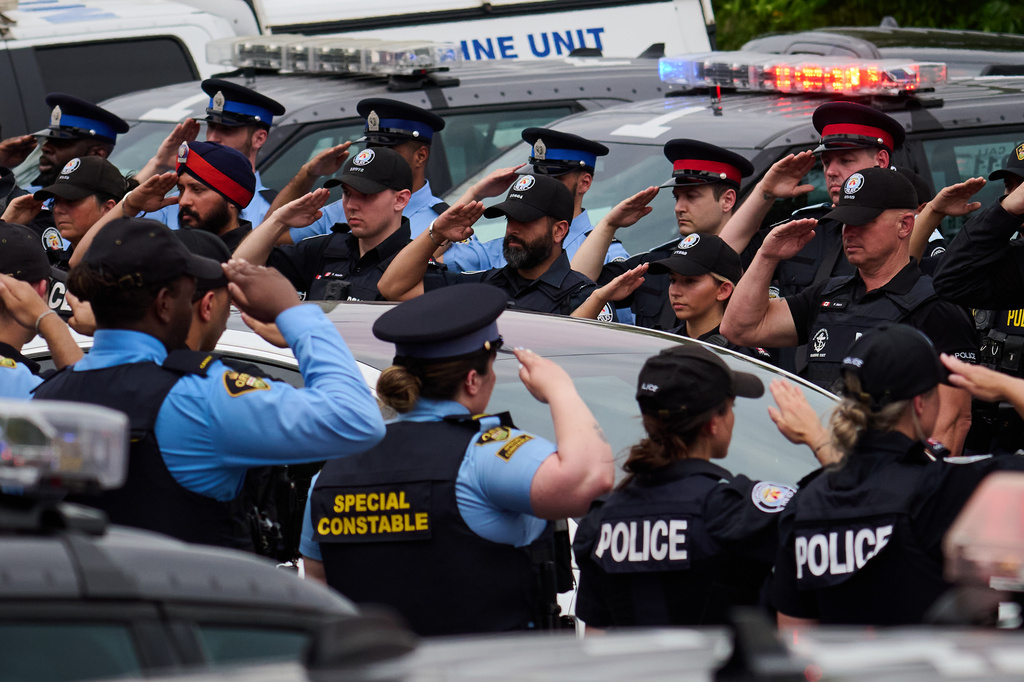 Police salute during a procession with the body of Toronto Police Const. Marc Pinizzotto, who was killed in the line of duty, at the Chief Coroner's office in Toronto, Thursday, June 11, 2026. (Sammy Kogan/The Canadian Press via AP)