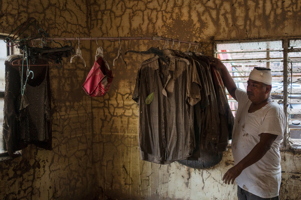 A man hangs recovered belongings inside a flooded house in Poza Rica, Veracruz state, Mexico, on Tuesday, Oct. 14, 2025, after landslides and torrential rain. (AP Photo/Felix Marquez)