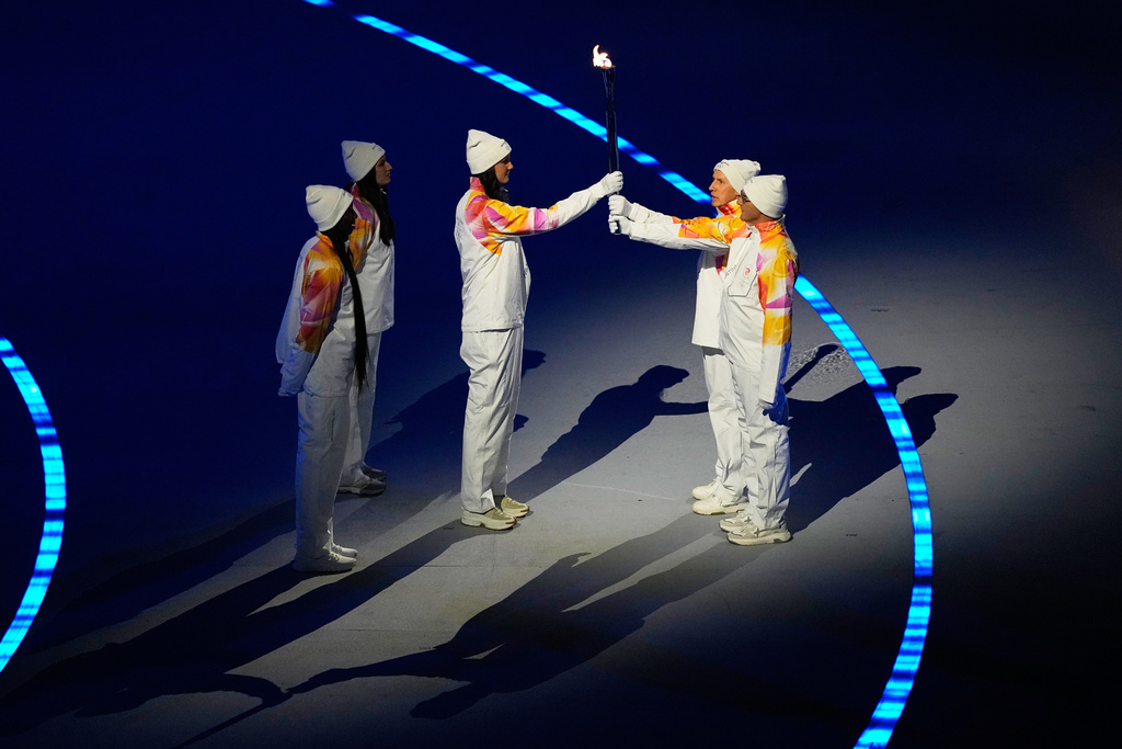 The Olympic torch is passed during the Olympic opening ceremony at the 2026 Winter Olympics, in Milan, Italy, Friday, Feb. 6, 2026. (AP Photo/Petr David Josek)