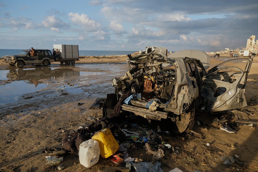 Palestinians drive past a destroyed car following an Israeli strike in Gaza City, Saturday, Dec. 13, 2025. (AP Photo/Jehad Alshrafi)