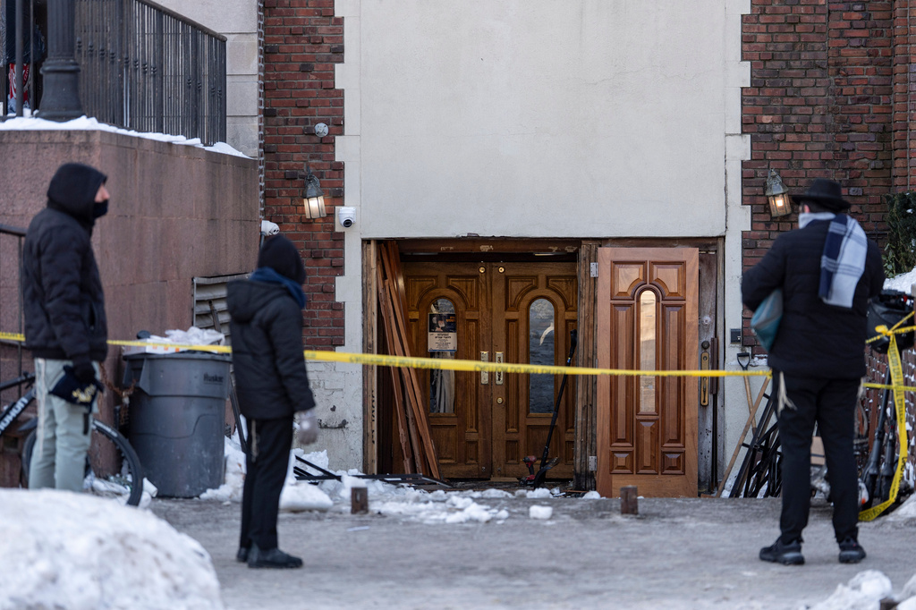 FILE - People watch the scene where a car slammed into the entrance of the Chabad Lubavitch world headquarters, Jan. 29, 2026, in New York. (AP Photo/Yuki Iwamura, File)
