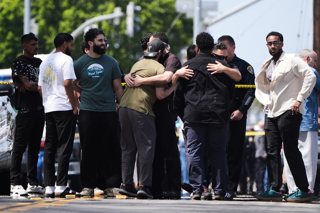 People embrace near the scene of a shooting outside the Islamic Center of San Diego Monday, May 18, 2026, in San Diego. (AP Photo/Gregory Bull)
