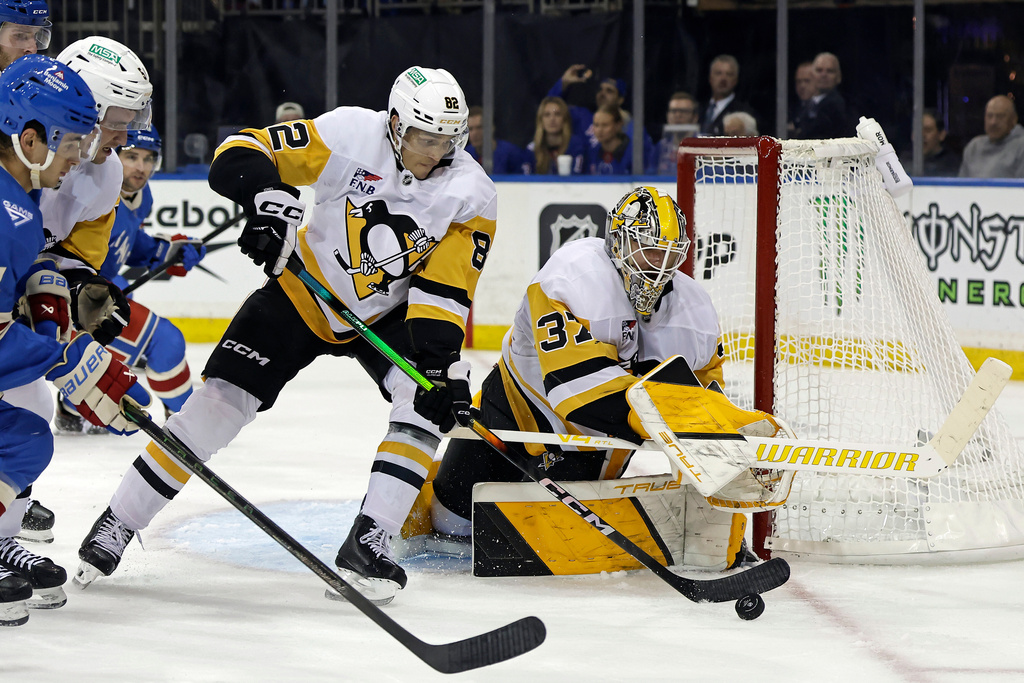 Pittsburgh Penguins defenseman Caleb Jones (82) clears the puck in front of goaltender Arturs Silovs (37) in the second period of an NHL hockey game against the New York Rangers, Tuesday, Oct. 7, 2025, in New York. (AP Photo/Adam Hunger)