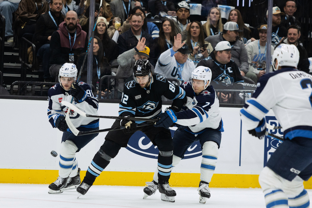 Utah Mammoth center Kevin Stenlund (82) fights for the puck against Winnipeg Jets center Cole Perfetti (91) and center Vladislav Namestnikov (7) during the first period of an NHL hockey game Sunday, Dec. 21, 2025, in Salt Lake City. (AP Photo/Melissa Majchrzak)