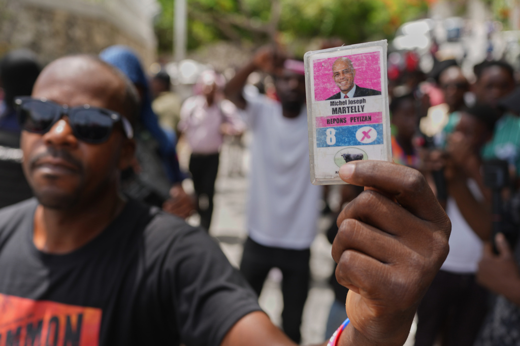 A supporter holds an outdated campaign flyer for former Haitian President Michel Martelly, who lives in the U.S., as he arrives home in Port-au-Prince, Haiti, Wednesday, July 15, 2026. (AP Photo/Odelyn Joseph)