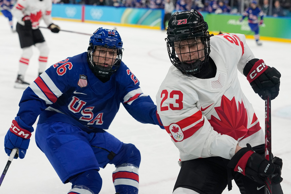 United States' Kendall Coyne (26) challenges with Canada's Erin Ambrose (23) during a women's ice hockey gold medal game between the United States and Canada at the 2026 Winter Olympics, in Milan, Italy, Thursday, Feb. 19, 2026. (AP Photo/Hassan Ammar)