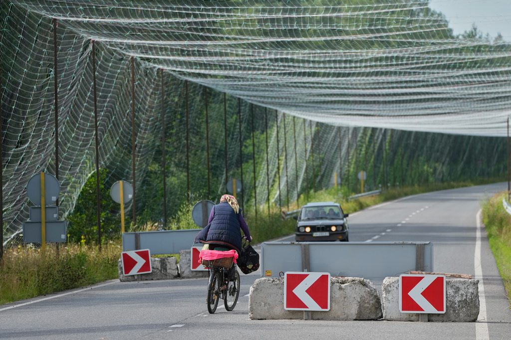 A local resident rides a bike under an anti-drone net close to the Ukraine-Belarus border in an undisclosed location in Ukraine Tuesday, July 7, 2026. (AP Photo/Efrem Lukatsky)
