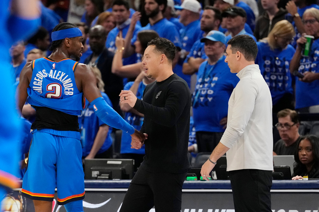 San Antonio Spurs head coach Mitch Johnson, center, talks with Oklahoma City Thunder guard Shai Gilgeous-Alexander (2) as Thunder head coach Mark Daigneault looks on during the second half of Game 7 of the Western Conference finals of the NBA basketball playoffs series Saturday, May 30, 2026, in Oklahoma City. (AP Photo/Tony Gutierrez)