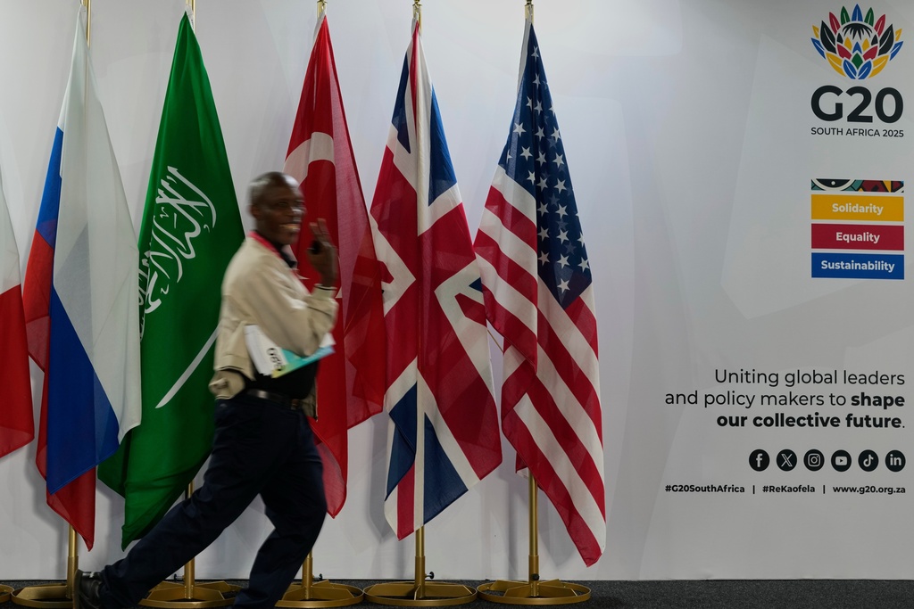 A journalist walks flags of participating country's at the media centre of the G20 Summit in Johannesburg, South Africa, Friday, Nov. 21, 2025. (AP Photo/Themba Hadebe)
