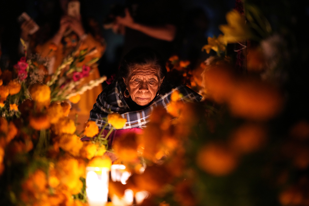 A woman sits next to the grave of a loved one celebrating the Day of the Dead at the cemetery of Tzintzuntzan, Michoacan state, Mexico, Friday, Oct. 31, 2025. (AP Photo/Eduardo Verdugo)