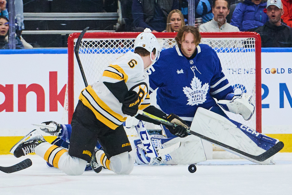 Toronto Maple Leafs goaltender Dennis Hildeby (35) loses his helmet as Boston Bruins' Mason Lohrei (6) searches for the puck during second period NHL hockey action in Toronto, on Saturday, Nov. 8, 2025. (Sammy Kogan/The Canadian Press via AP)