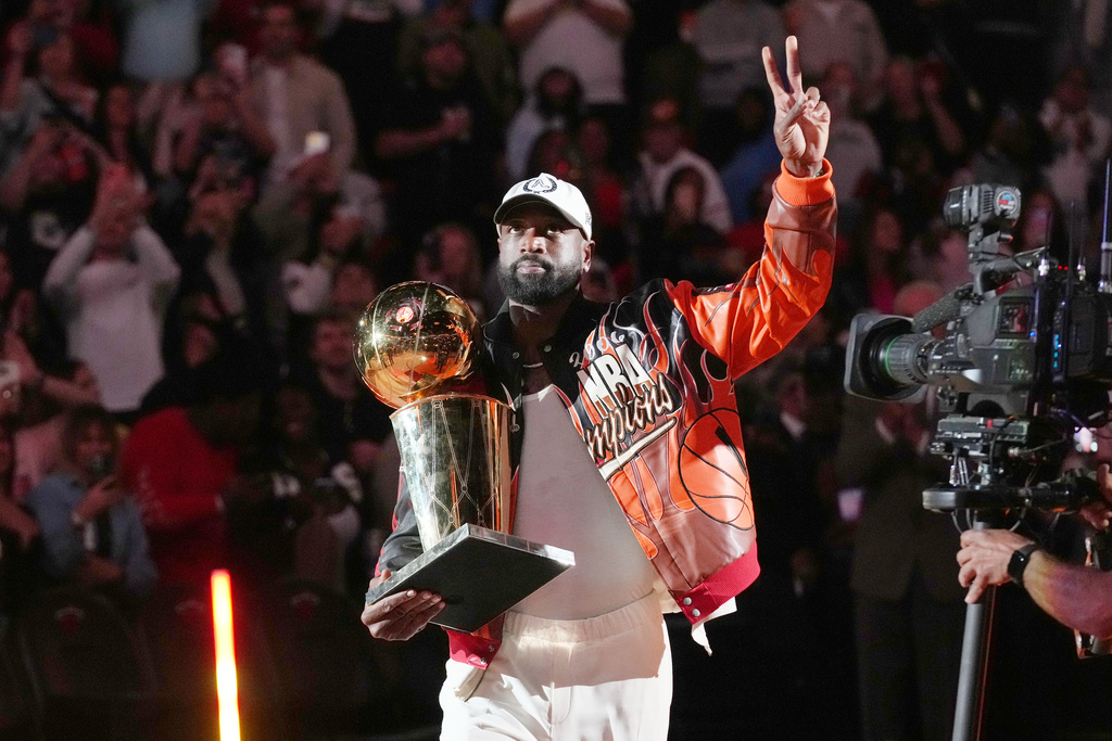 Miami Heat former player Dwyane Wade carries the 2006 NBA trophy during a half time celebrating of the team Tuesday, Feb. 3, 2026, in Miami. (AP Photo/Marta Lavandier)