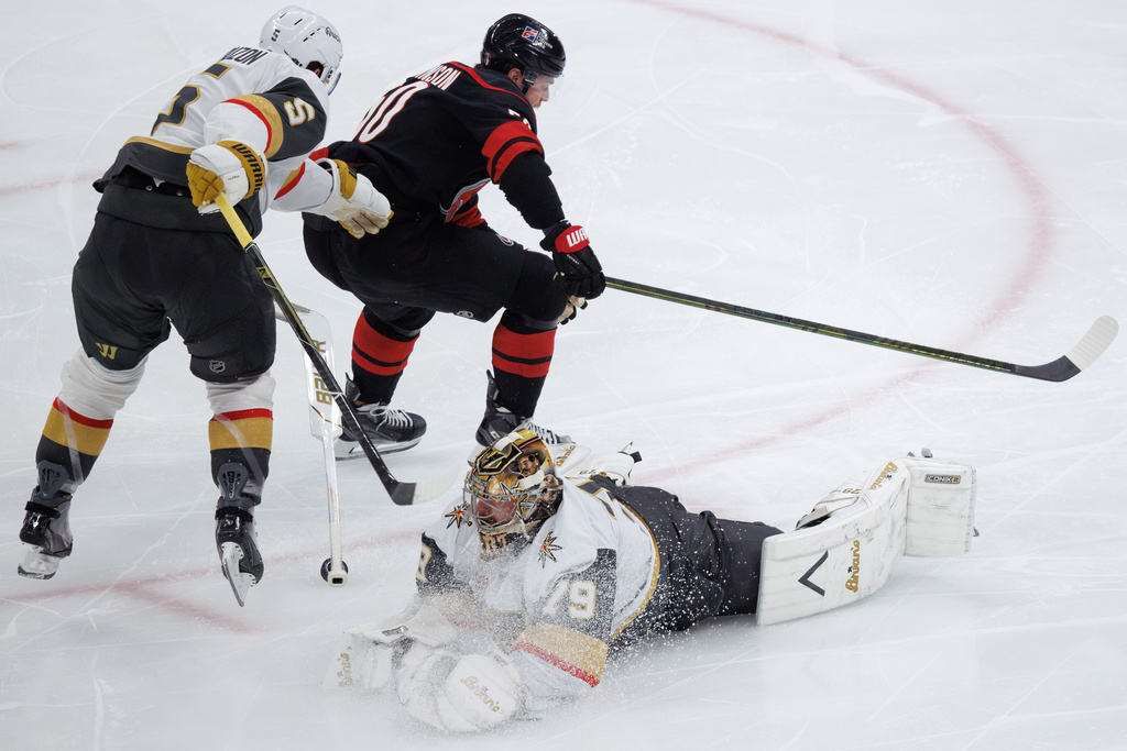 Vegas Golden Knights' goaltender Carter Hart (79) loses his stick as he dives for the puck past teammate Jeremy Lauzon (5) and Carolina Hurricanes' Eric Robinson, top right, during the third period of Game 5 of the NHL hockey Stanley Cup Final series in Raleigh, N.C., Thursday, June 11, 2026. (AP Photo/Ben McKeown)