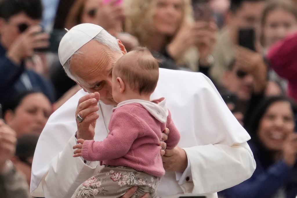 Pope Leo XIV blesses a child as he arrives for his weekly general audience in St. Peter's Square, at the Vatican, Wednesday, May 6, 2026. (AP Photo/Gregorio Borgia)