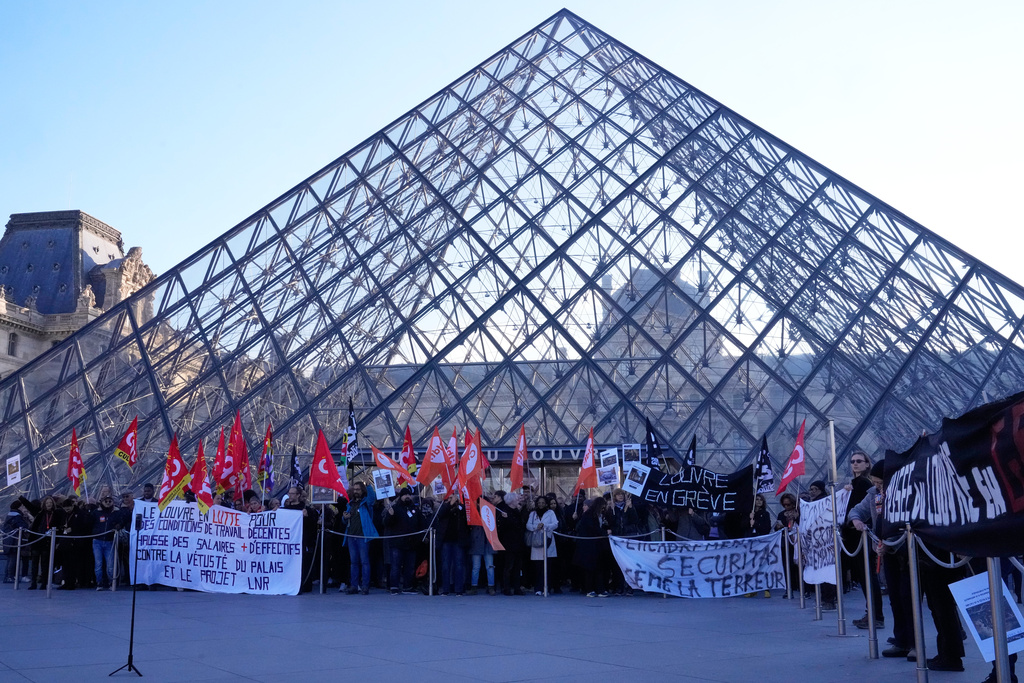 Workers display banners outside the Louvre museum after they voted to strike for the day over working conditions and other complaints, Monday, Dec. 15, 2025 in Paris. (AP Photo/Michel Euler)