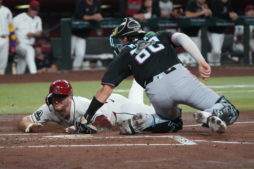 Arizona Diamondbacks' Pavin Smith, left, steals home under a tag by Miami Marlins catcher Joe Mack, right, in the third inning of a baseball game, Monday, Sept 14, 2026, in Phoenix. (AP Photo/Rick Scuteri)
