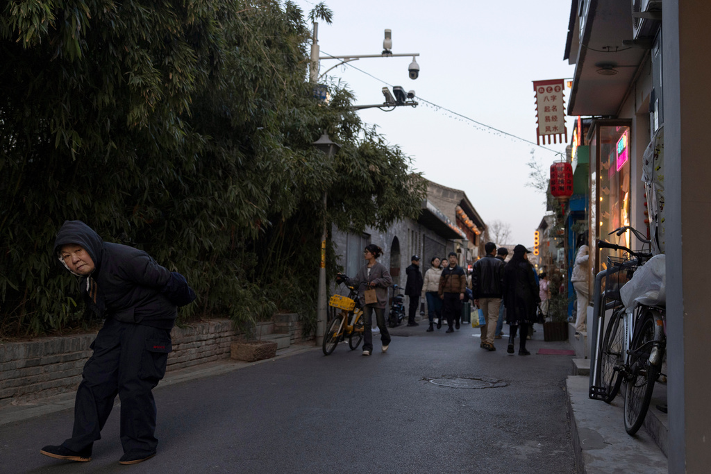 An elderly woman walks along the popular Nanluogu alleyway past security cameras in Beijing, Saturday, Feb. 15, 2025. (AP Photo/Ng Han Guan)