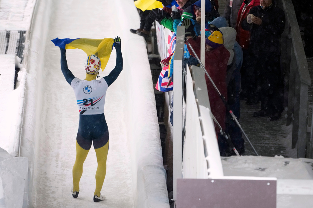 FILE - Valdyslav Heraskevych, of Ukraine, waves a flag as he finishes his second run during the World Cup skeleton competition in Lake Placid, N.Y., March 21, 2024. (AP Photo/Seth Wenig)