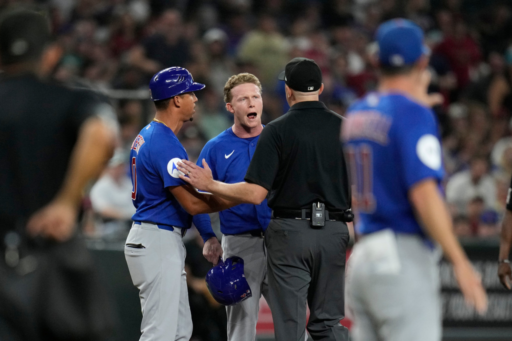 Chicago Cubs' Pete Crow-Armstrong, center, and Cubs third base coach Quintin Berry (0) argue with umpire Lance Barrett during the sixth inning of a baseball game against the Arizona Diamondbacks, Wednesday, Aug. 26, 2026, in Phoenix. (AP Photo/Ross D. Franklin)