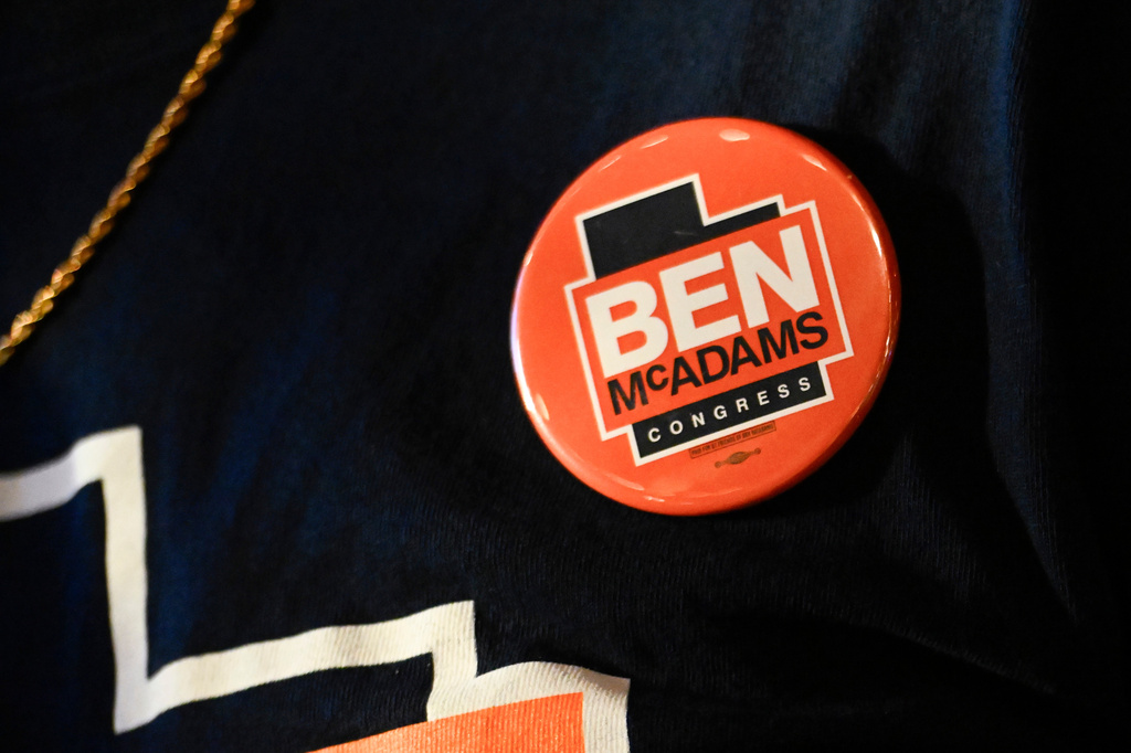 A supporter wears a button for candidate Ben McAdams speaks during a watch party for Utah's primary election on Tuesday, June 23, 2026, in Salt Lake City. (AP Photo/Alex Goodlett)