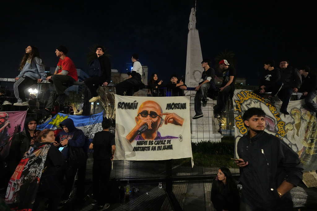 People gather near a drawing depicting Carlos Alberto Solari, the Argentine singer-songwriter known as "the Indio" who led Patricio Rey y sus Redonditos de Ricota, on the day of his death, at Plaza de Mayo square in Buenos Aires, Argentina, Friday, June 5, 2026. (AP Photo/Gustavo Garello)