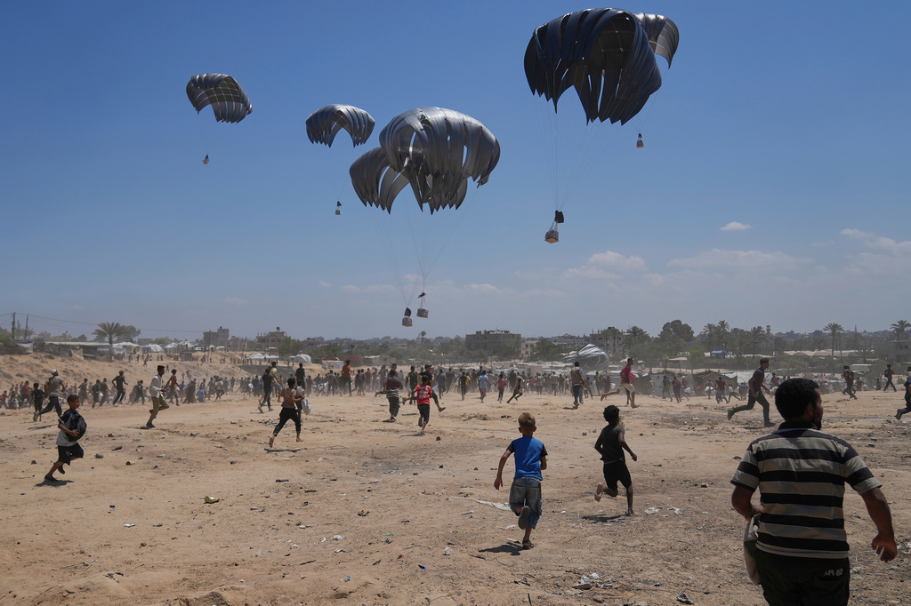 FILE - Palestinians rush to collect humanitarian aid airdropped by parachutes into Zawaida in the central Gaza Strip, Monday, Aug. 4, 2025. (AP Photo/Abdel Kareem Hana, File)