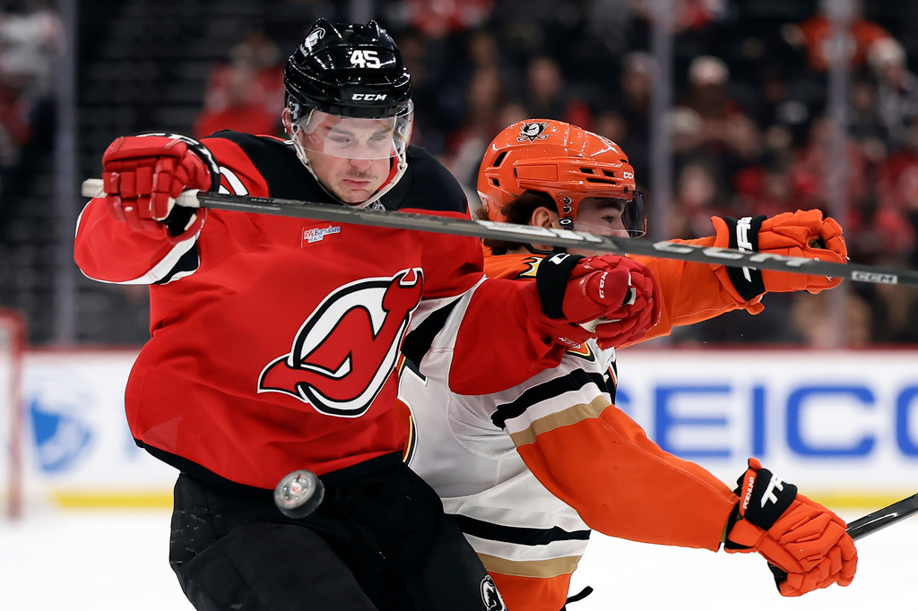 New Jersey Devils defenseman Colton White (45) collides with Anaheim Ducks center Ryan Poehling chasing down a puck during the first period of an NHL hockey game Saturday, Dec. 13, 2025, in Newark, N.J. (AP Photo/Adam Hunger)