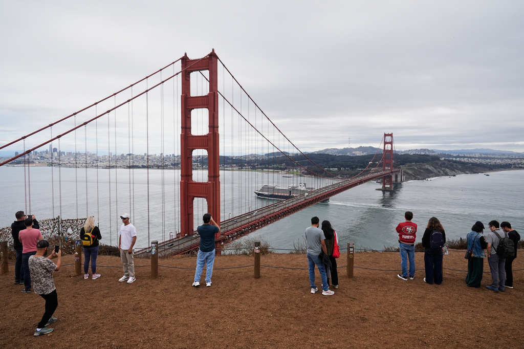 FILE - People look at and photograph the Golden Gate Bridge while visiting Marin Headlands, which is part of the Golden Gate National Recreation Area, Oct. 1, 2025, in Mill Valley, Calif. (AP Photo/Godofredo A. Vásquez, File)