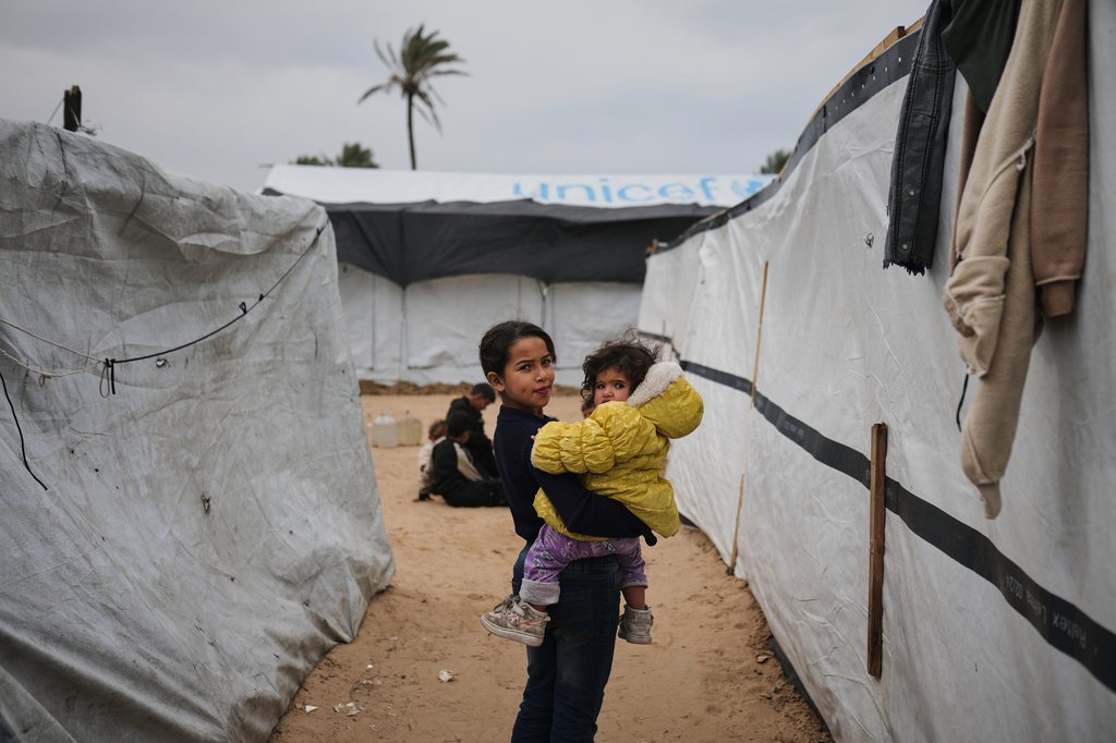 Palestinian children walk between tents at an orphanage camp in Khan Younis, southern Gaza Strip, Thursday, Jan. 22, 2026. (AP Photo/Jehad Alshrafi)