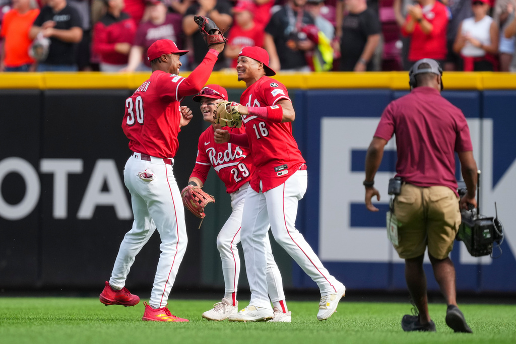 Cincinnati Reds' Noelvi Marte (16) celebrates with teammates Will Benson (30) and TJ Friedl (29) following a baseball game against the Pittsburgh Pirates, Thursday, Sept. 25, 2025, in Cincinnati. (AP Photo/Jeff Dean)