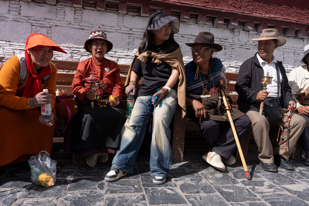 Qongqiu Quco, a 19-year-old student, sits with her relatives outside Jokhang Temple in Lhasa in western China's Tibet autonomous region on July 21, 2026, during a government- organized visit for foreign journalists. (AP Photo/Ng Han Guan)