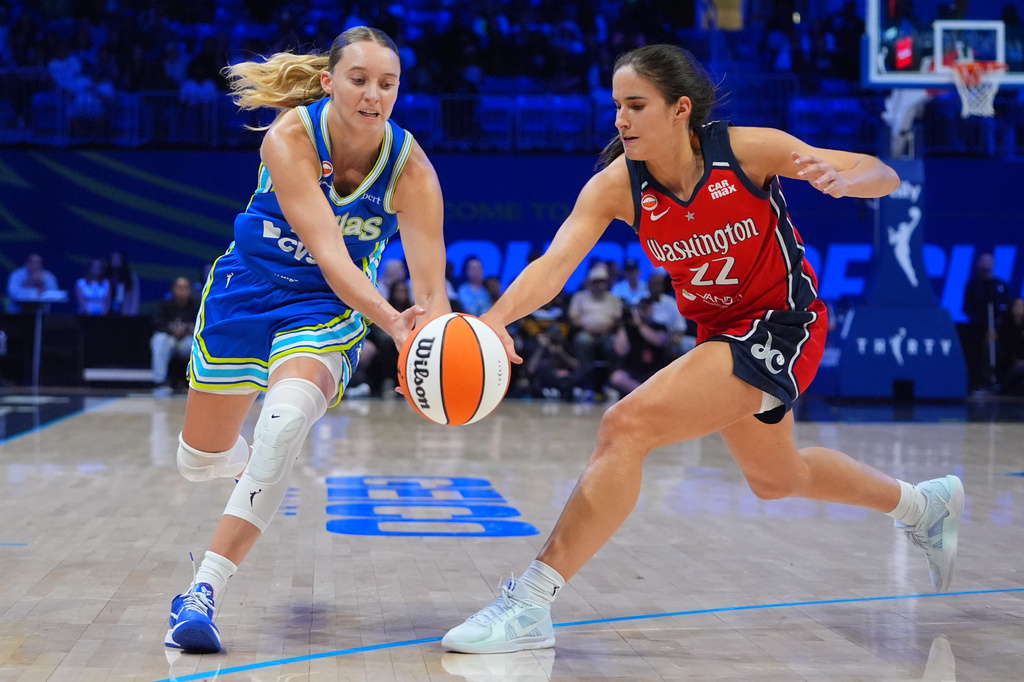 Dallas Wings guard Paige Bueckers, left, and Washington Mystics guard Sonia Citron (22) reach for the ball during the second half of a WNBA basketball game in Arlington, Texas, Monday, May 18, 2026. (AP Photo/LM Otero)